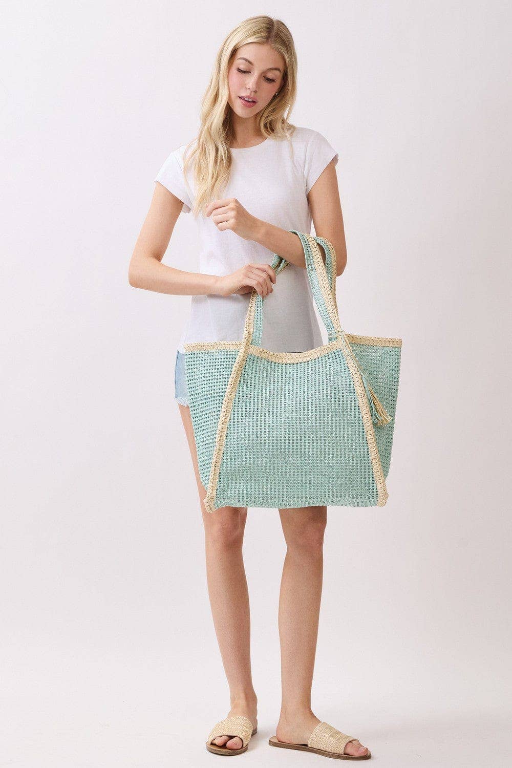 Two-tone woven straw beach tote bag with leather handles, stylish and spacious for summer beach outings.
