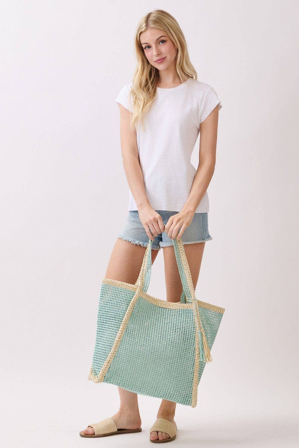 Two-tone woven straw beach tote bag with leather handles, stylish and spacious for seaside outings and beach days.