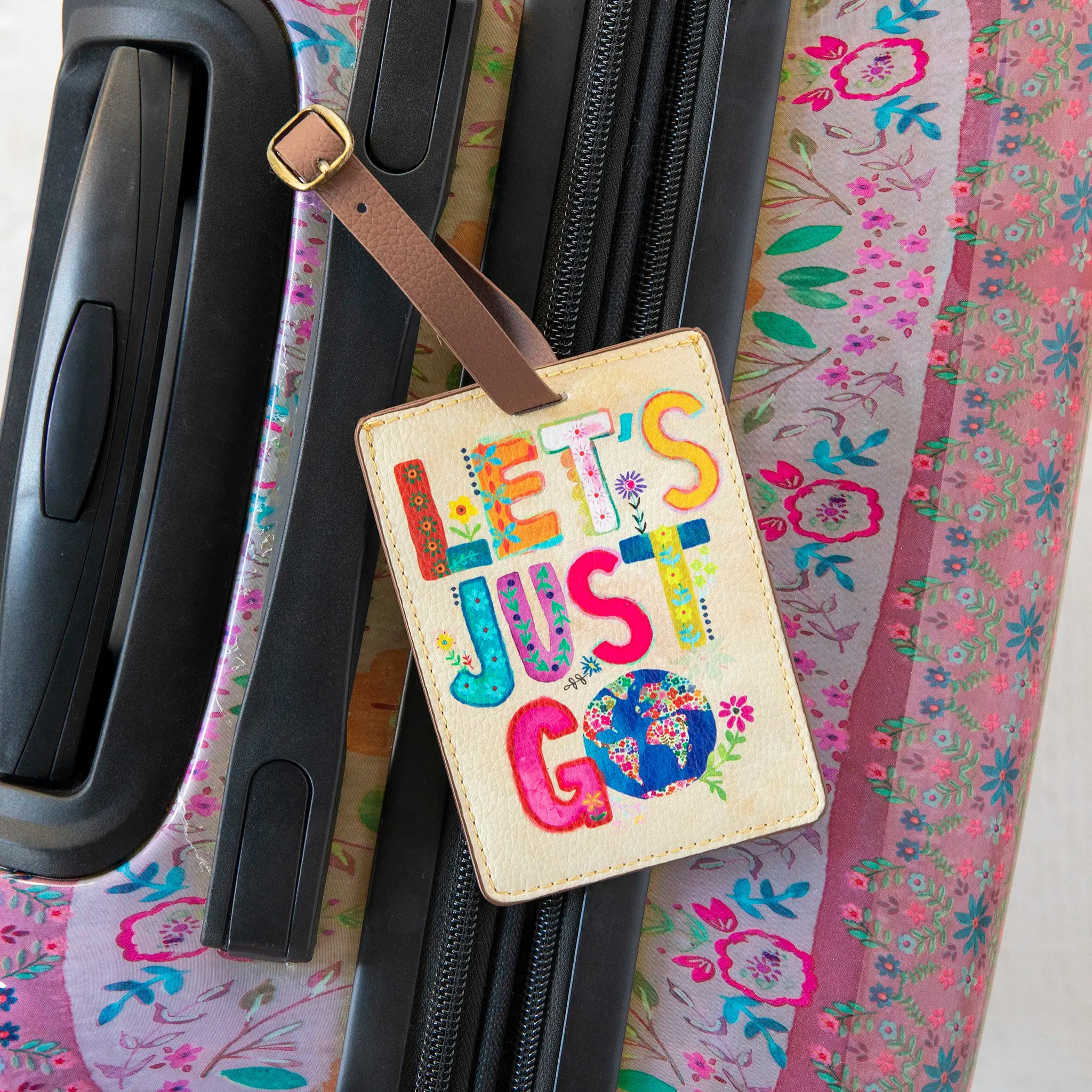 Natural Life Travel Happy luggage tag with "Let's Just Go" design, featuring colorful travel-themed imagery.