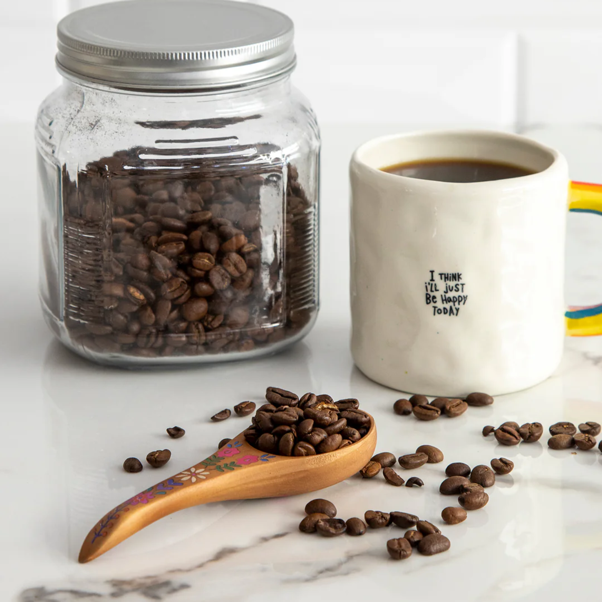 Natural Life wooden coffee scoop with "But First Coffee" engraved, featuring a curved handle and rustic design.