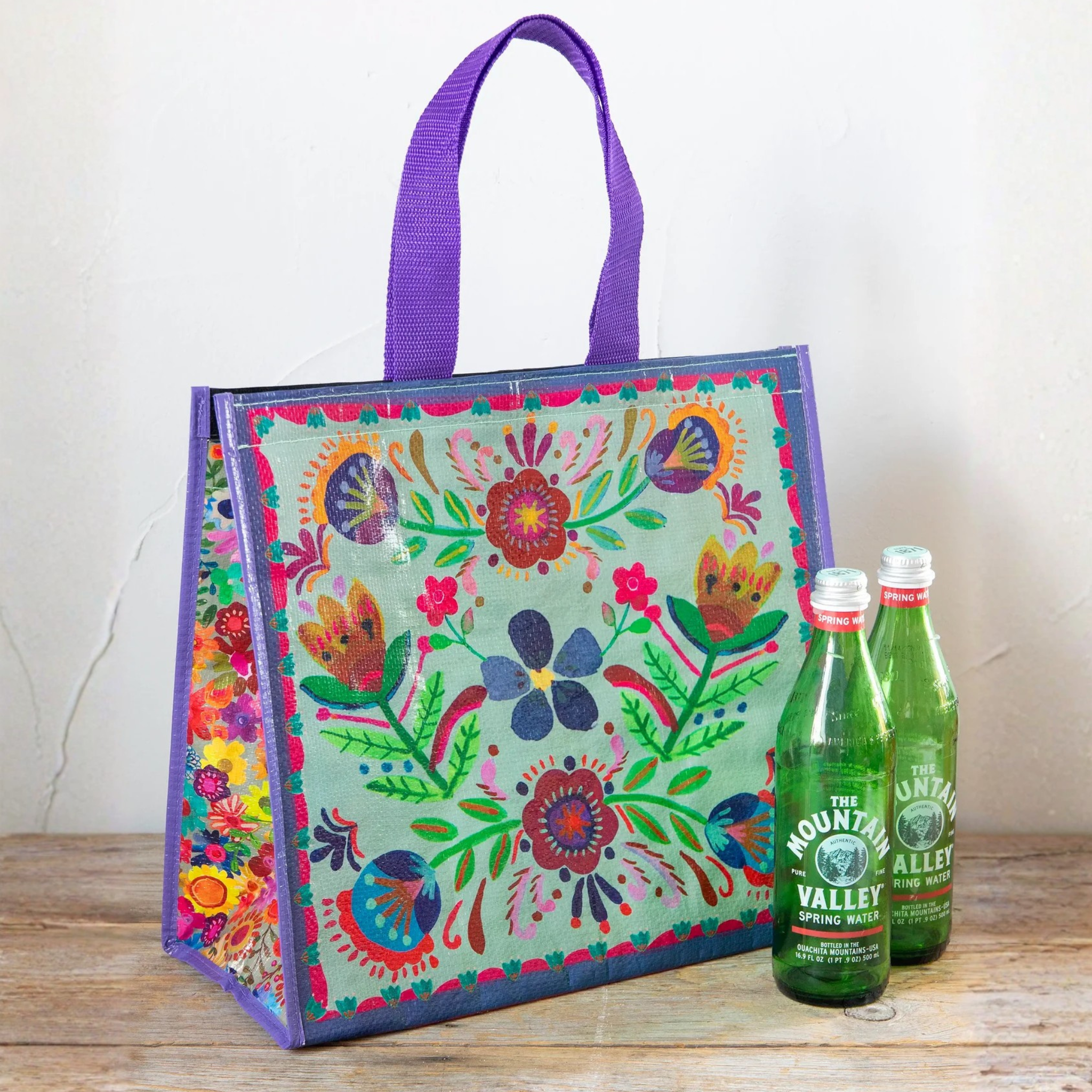 Natural Life insulated cooler tote in dusty blue with folk flower pattern, showing its insulated interior and stylish design.
