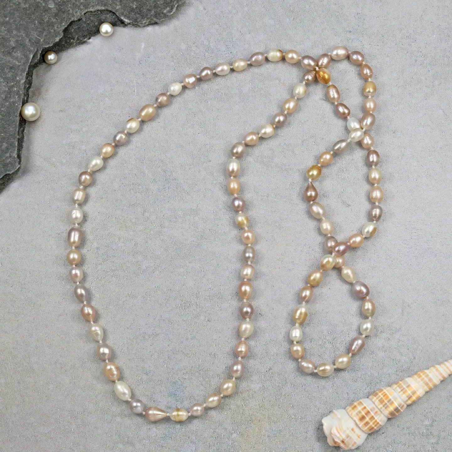 Pearl necklace on a gray surface with a shell