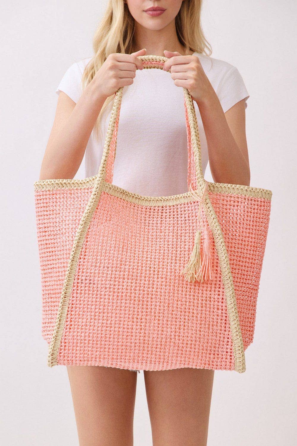Two-tone woven straw beach tote bag with leather handles, stylish and spacious for carrying essentials to the beach.