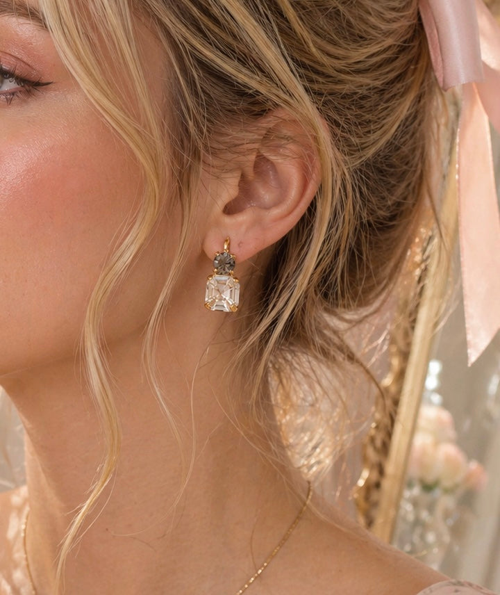 Sorrelli Kimber dangle earrings with intricate silver-tone design and sparkling gemstone accents, hanging from the ears.