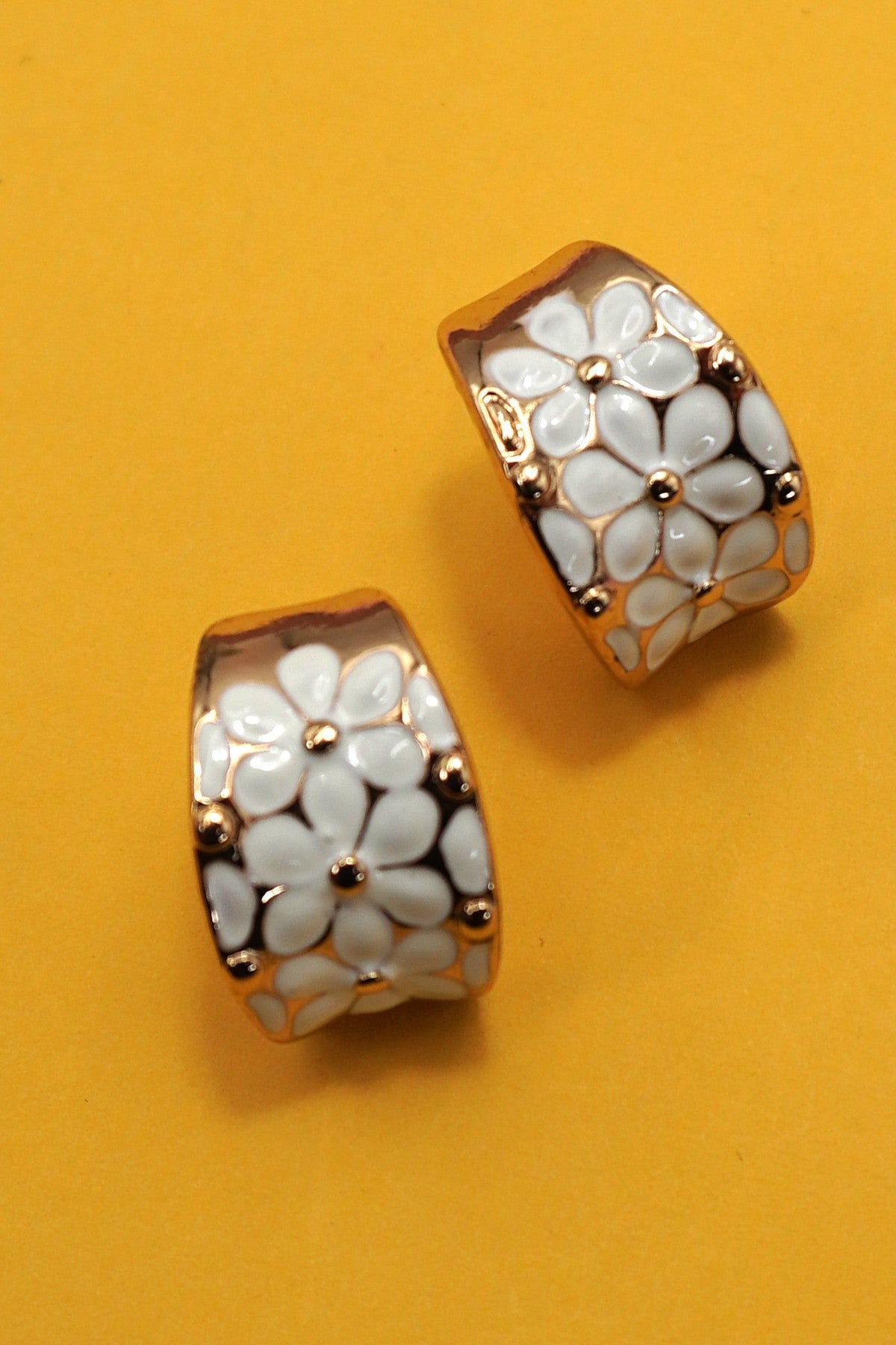 Pair of earrings with floral design on a yellow background
