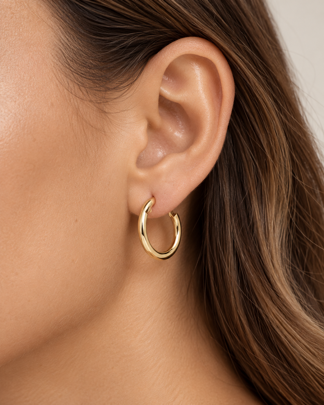 Private label 20mm gold hoop earrings, sleek and shiny hoops made of gold, showcasing their circular design and polished finish.