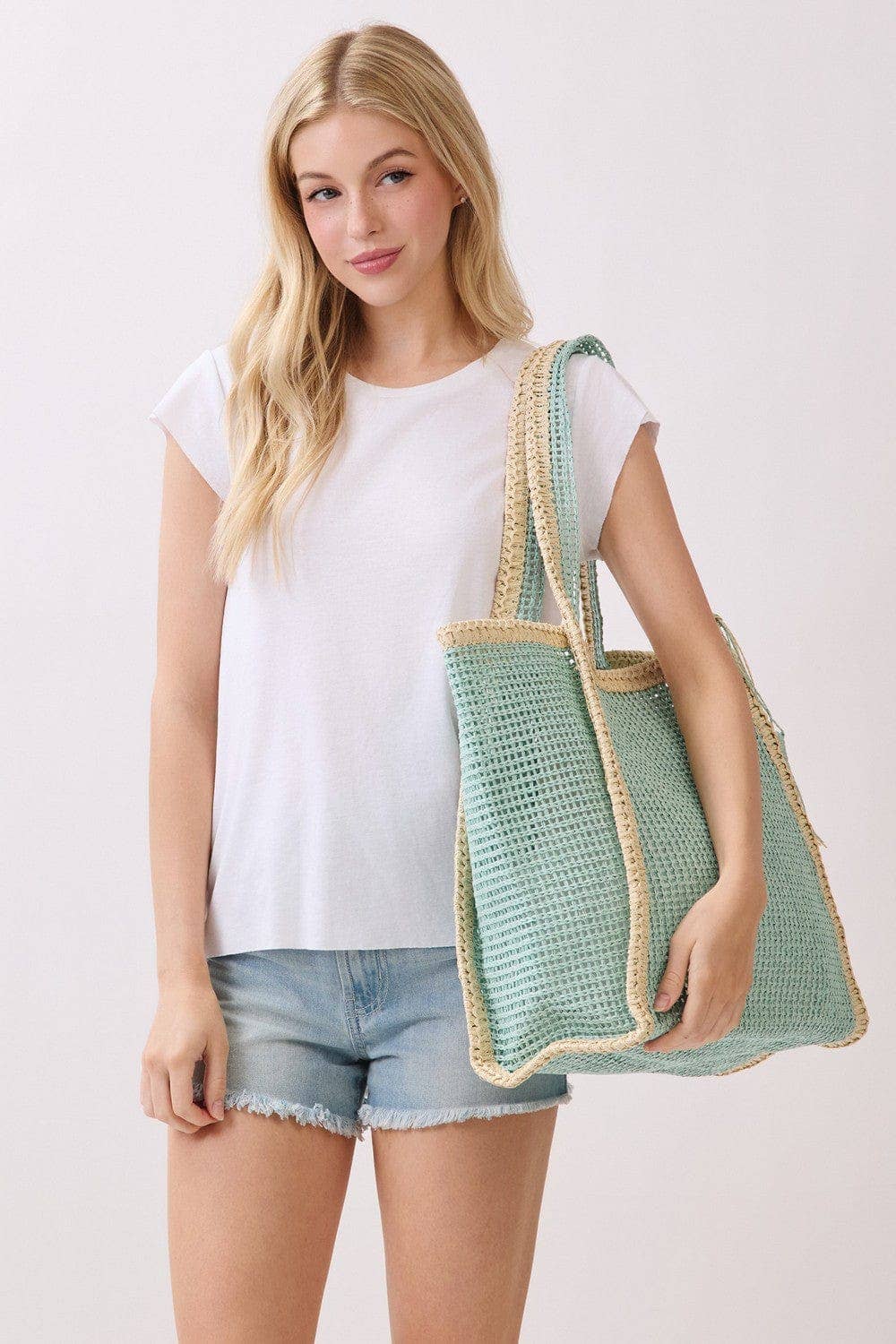 Two-tone woven straw beach tote bag with leather handles, stylish and spacious for summer beach outings.