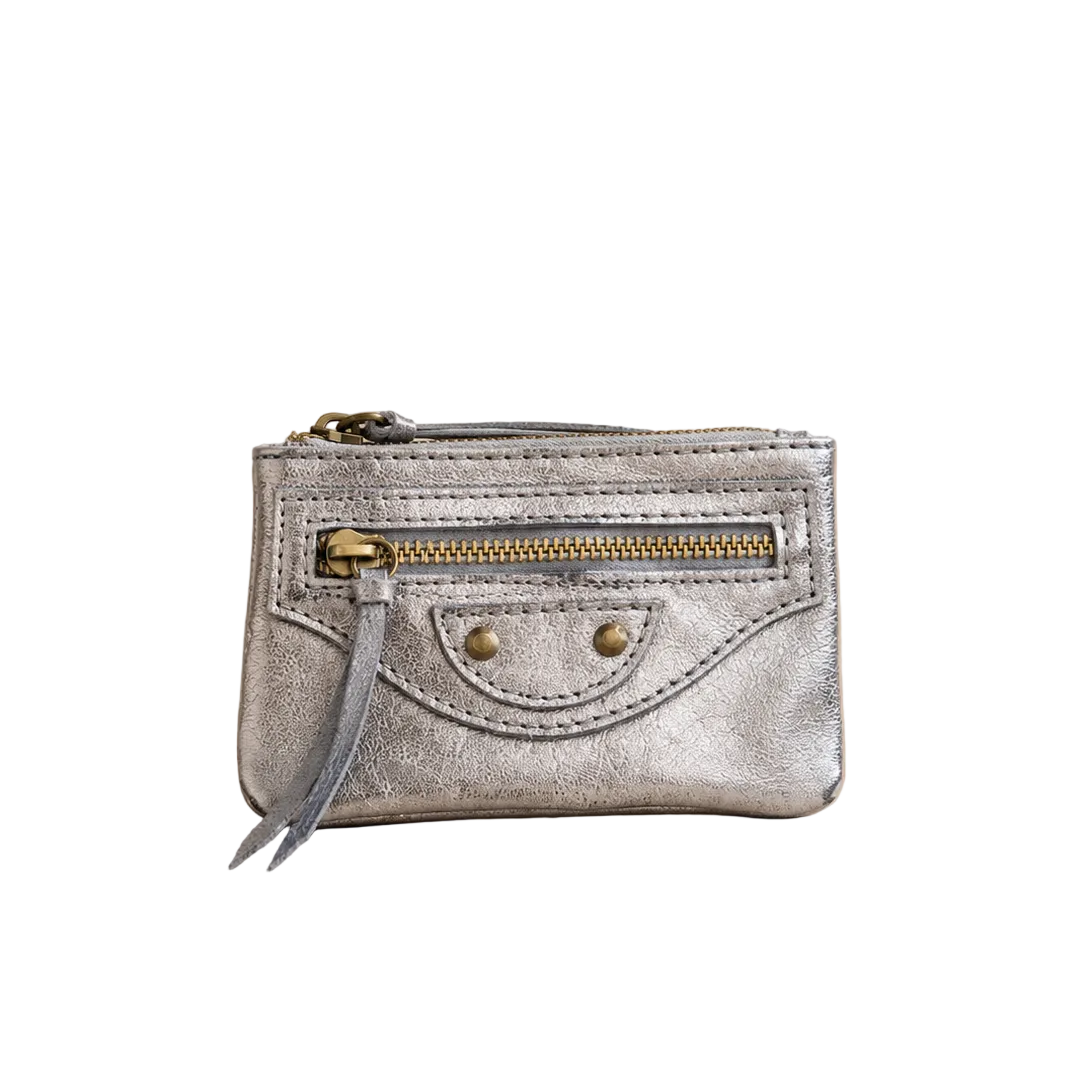 Silver metallic wallet with a gold zipper on a beige background