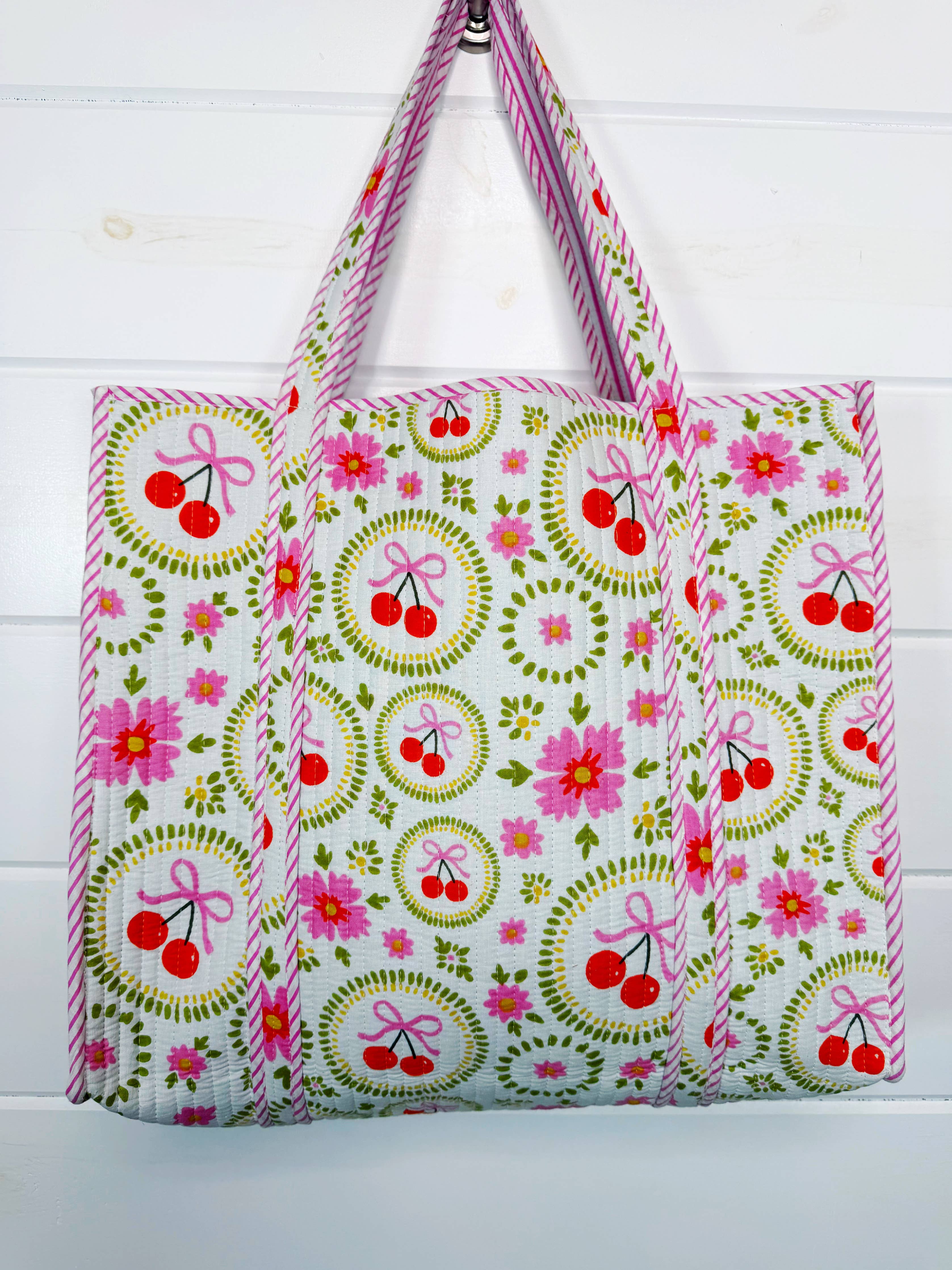 White quilted Folklore Couture large tote bag with cherry and bow details, perfect for travel and everyday use.