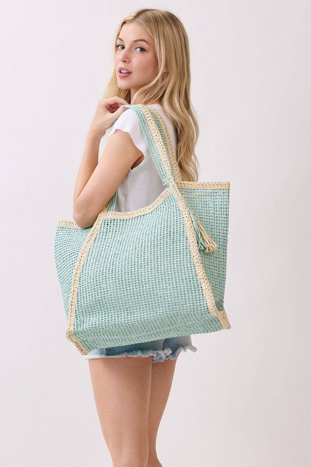 Two-tone woven straw beach tote bag with leather handles, stylish and spacious for summer beach outings.