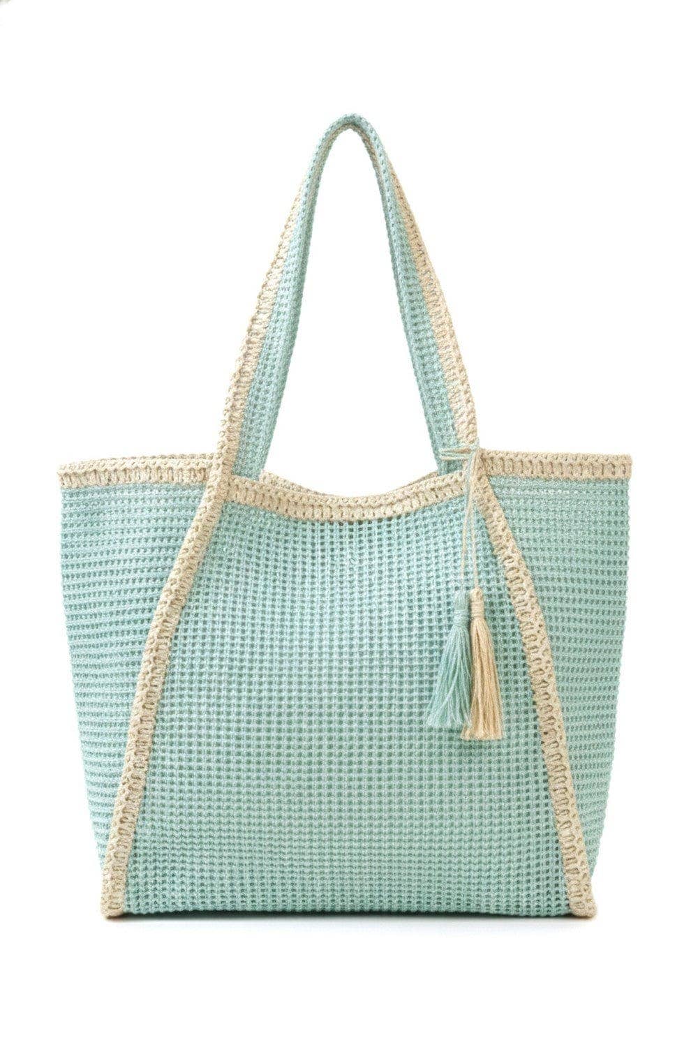 Two-tone woven straw beach tote bag with leather handles, stylish and spacious for carrying essentials at the beach.