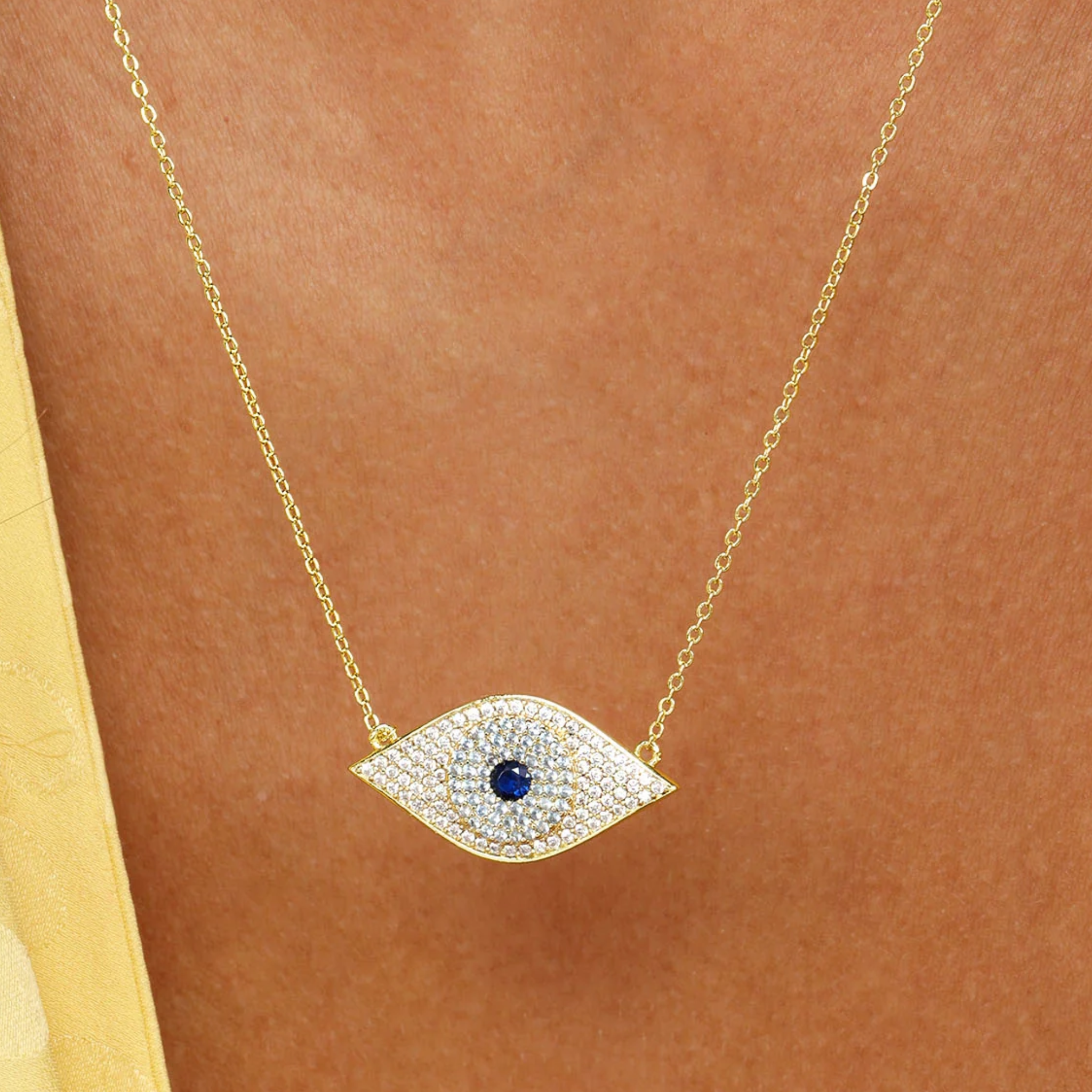 Blue evil eye necklace with gold chain and white diamondette accents by Melinda Maria, showcasing a protective jewelry design.