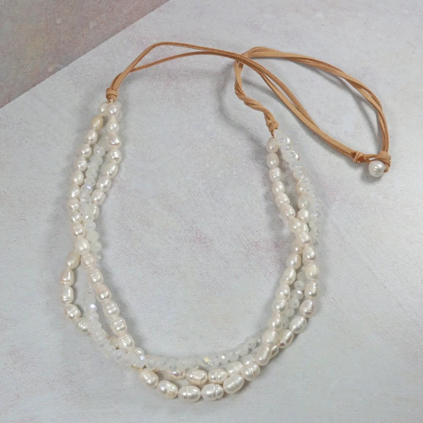 Pearl necklace with leather strap on a light gray background