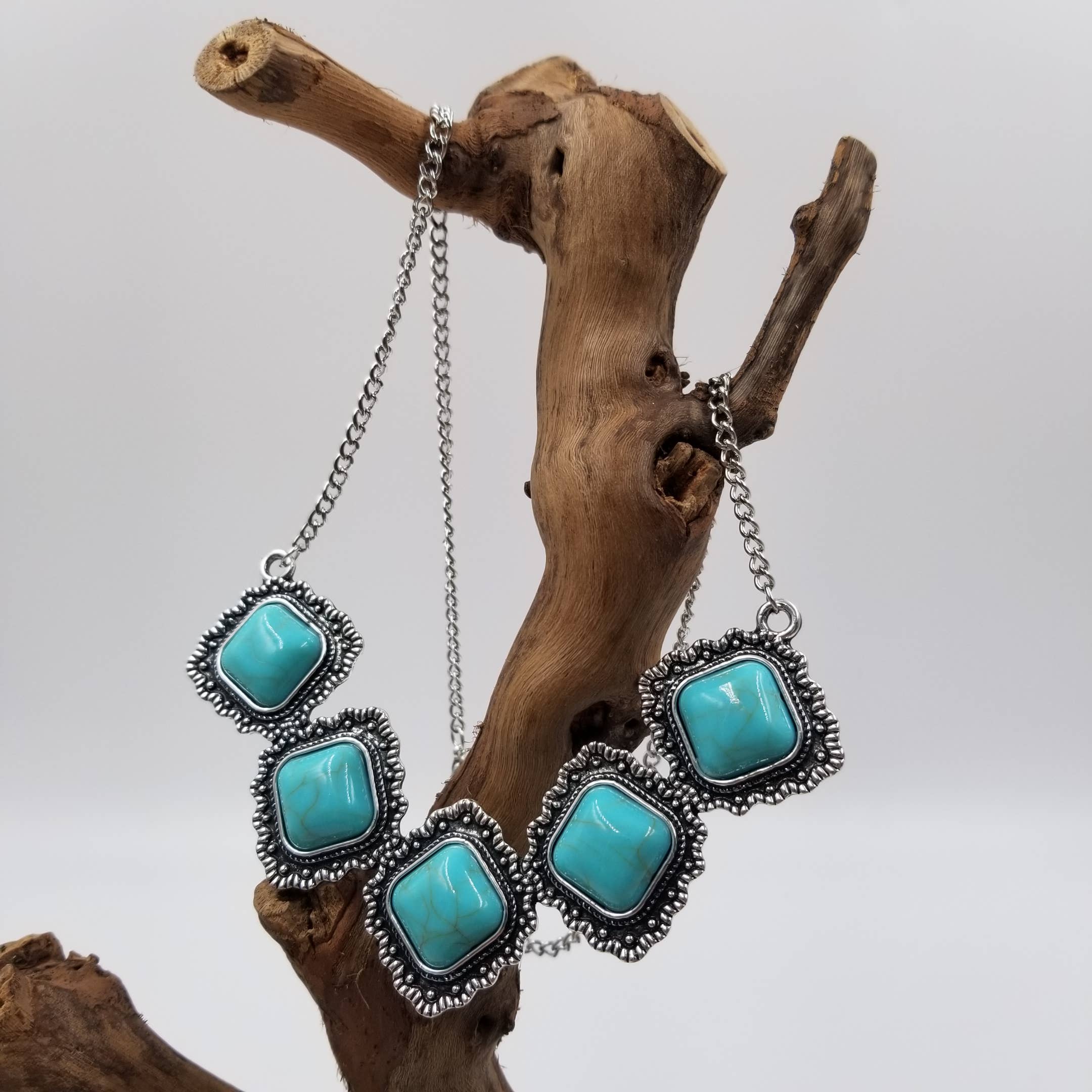 Turquoise necklace with silver chain on a wooden branch