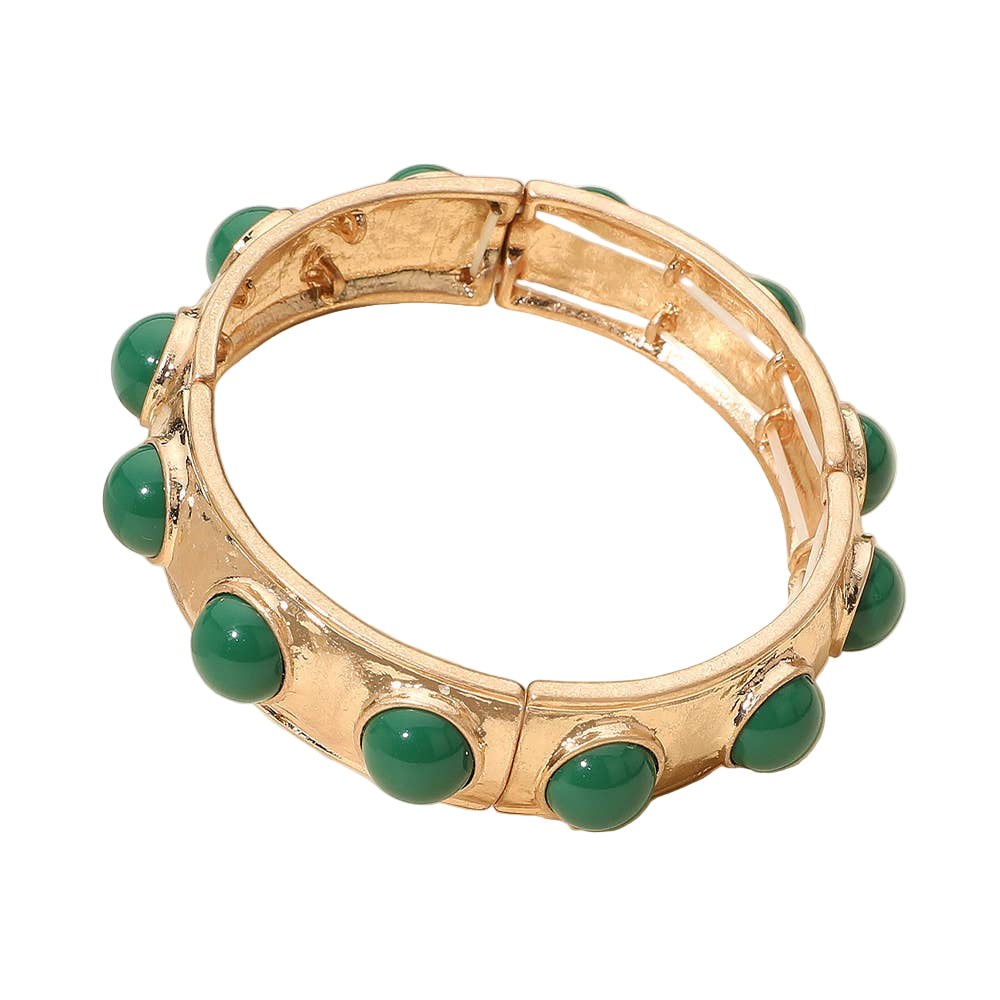 Gold bracelet with green stones on a light background