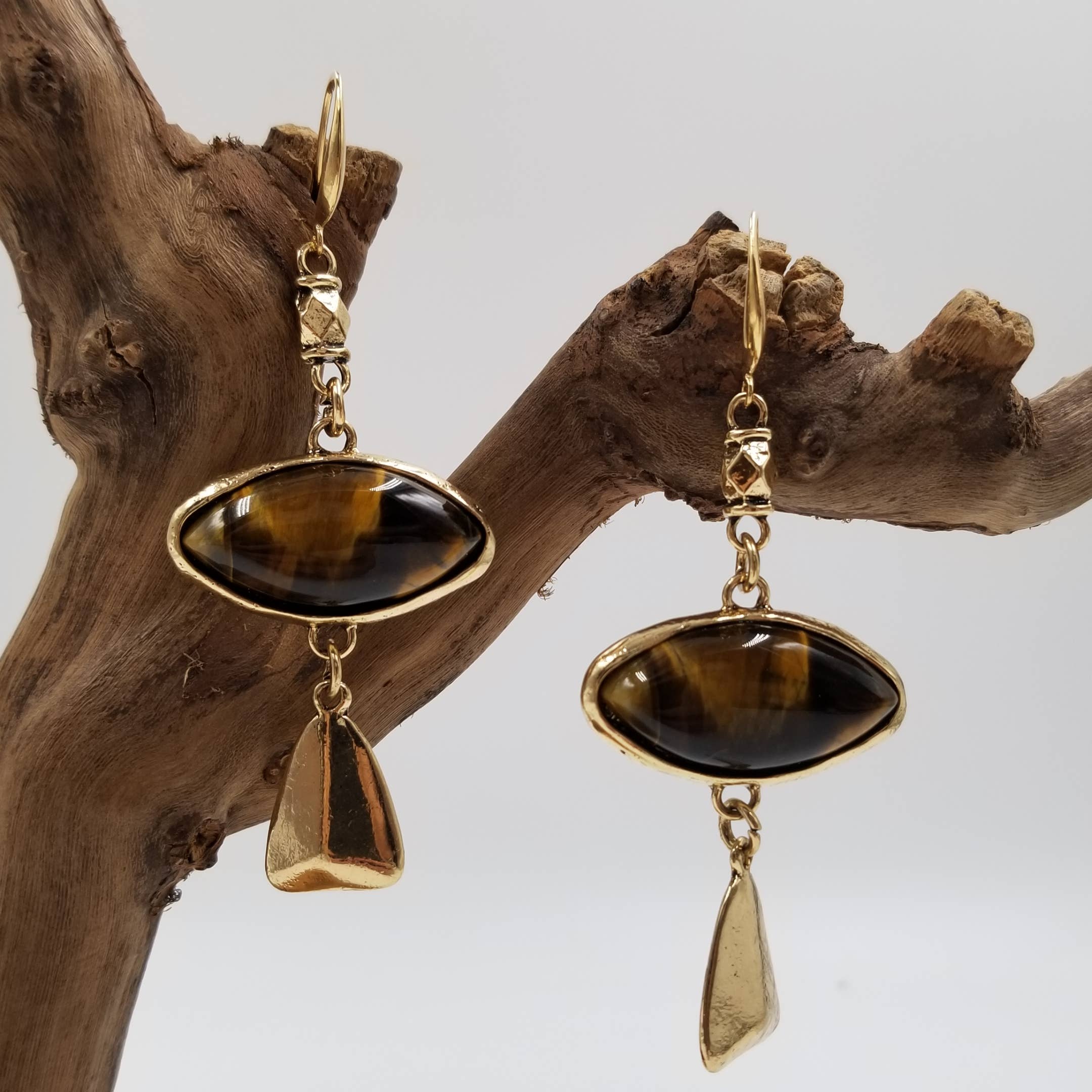 Gold earrings with brown gemstones on a wooden branch