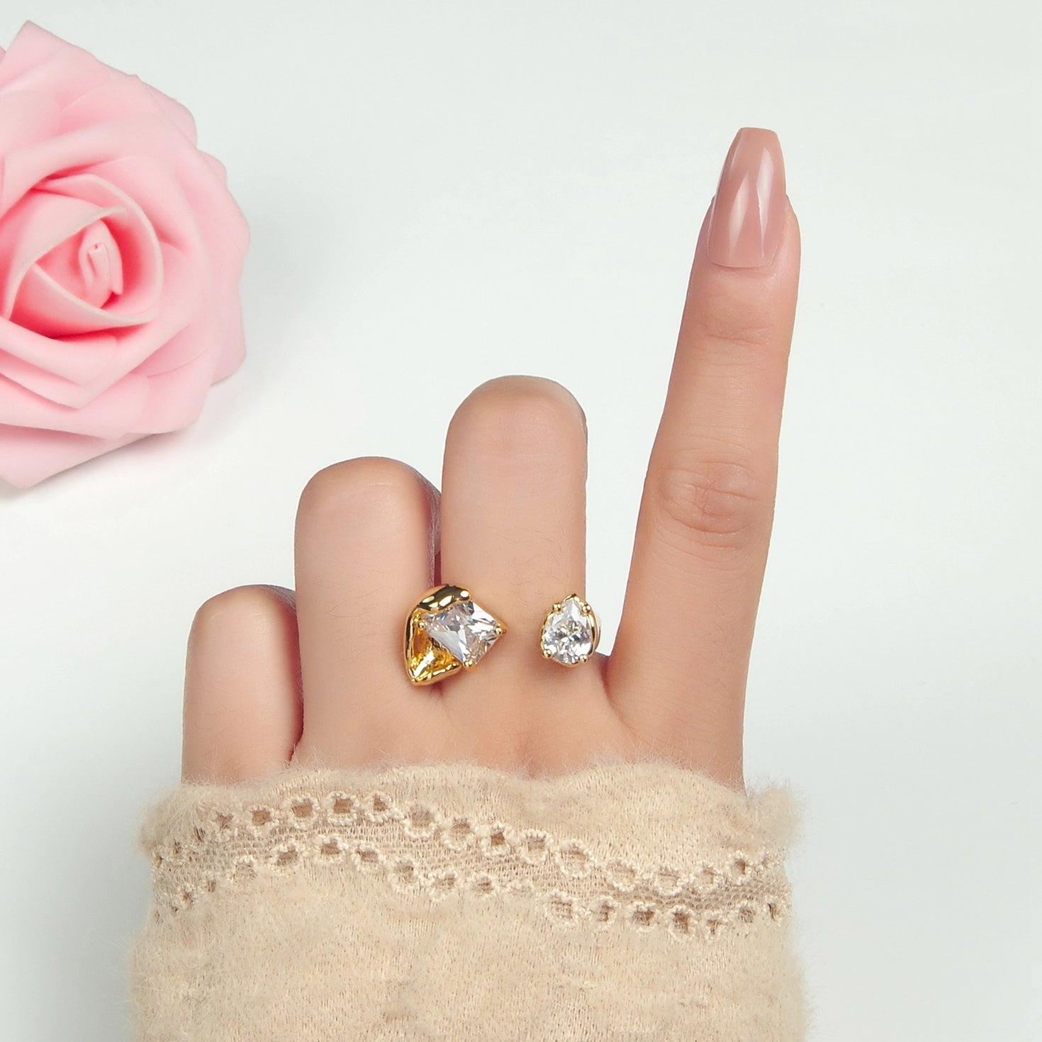 Gold and silver ring on a finger with a pink rose in the background