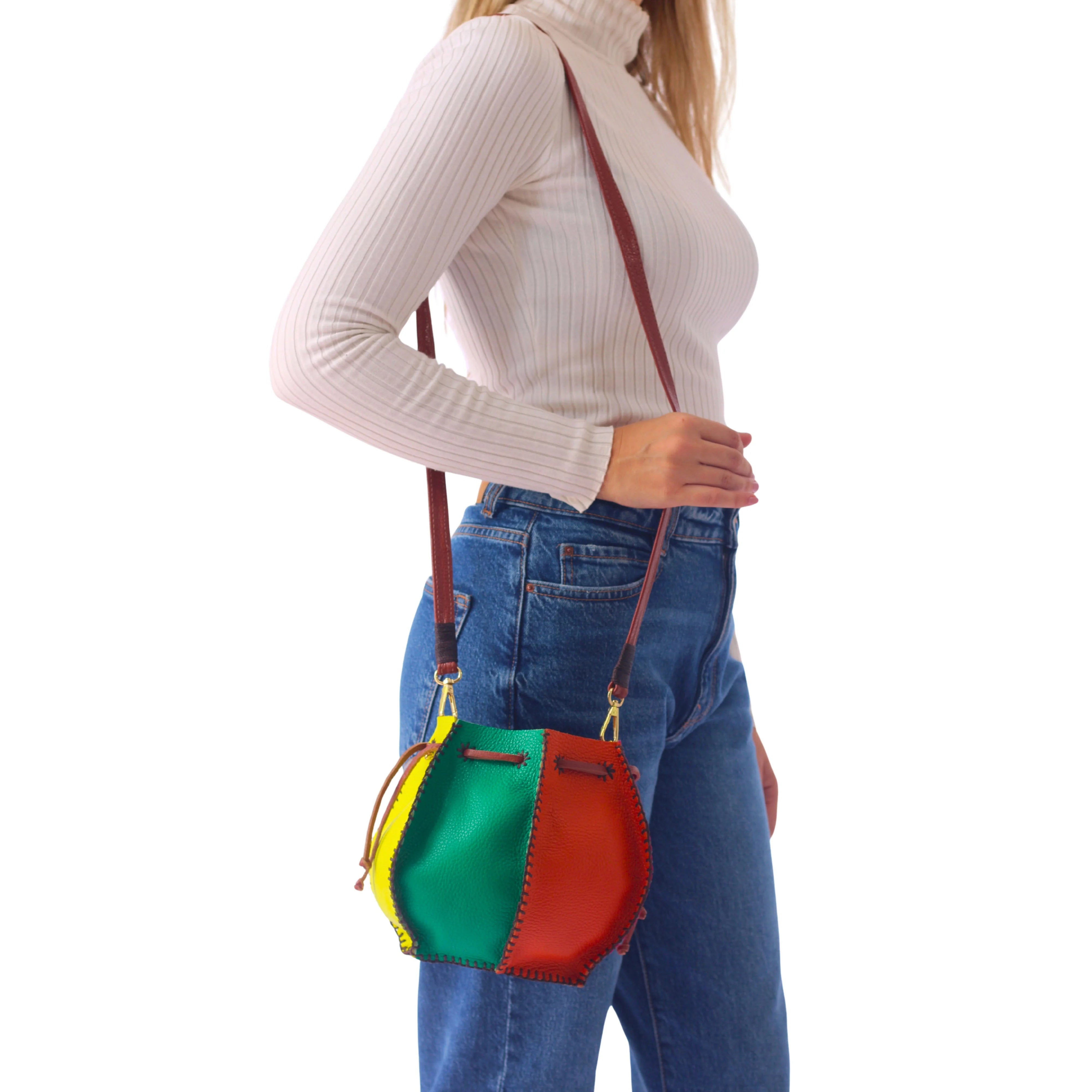 Colorful rainbow tall bucket bag by Carlos Falchi with a vibrant, rainbow-colored exterior and structured design.